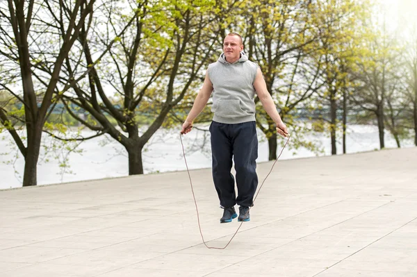 Man with jump rope in park.