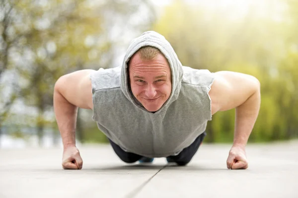 Active man doing push up in park.