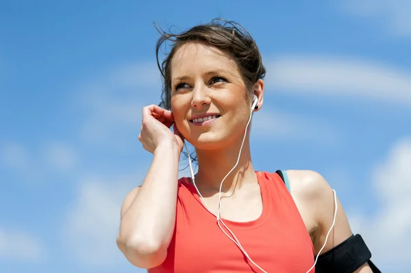 Fit woman jogger resting after run listening music.