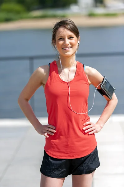 Fit woman jogger resting after run listening music. Smiling.