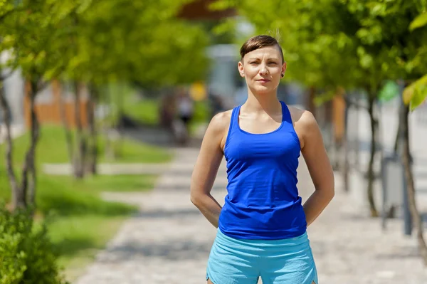 Women jogger in park smiling. Standing in park.