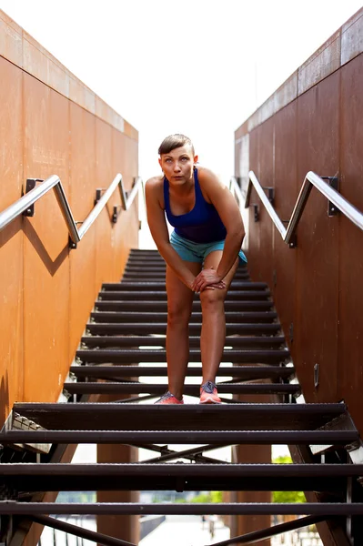 Fit woman resting after run on stairs.