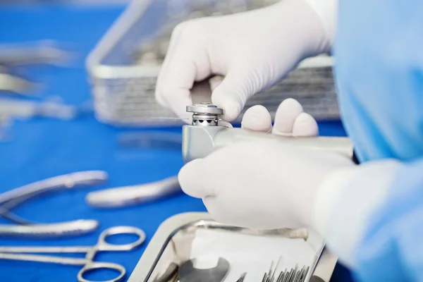 Close-up of scrub nurse taking medical instruments for operation