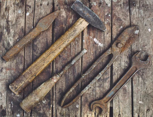 Old, rusty tools lying on a wooden table. Hammer, chisel, metal