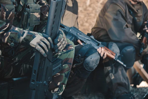 Two soldiers in camouflage and gloves keep the hands in the machines.