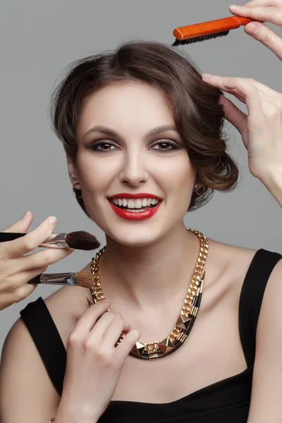 Beautiful woman with evening make up surrounded by the different brushes for make up