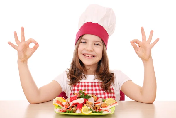 快乐的小女孩煮海鲜和 ok 手势 - 图库照片goce