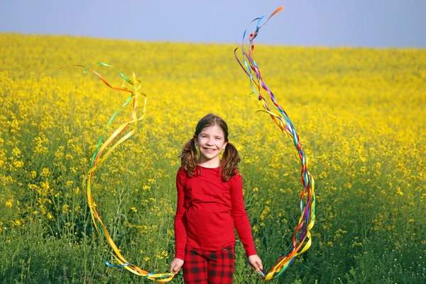 Happy little girl playing on yellow flowers field