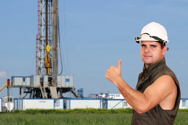 Oil worker thumb up and land drilling rig