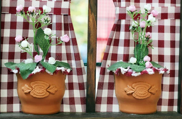 Two vases with flowers on window