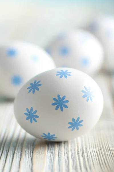 White eggs with blue pattern on wooden background