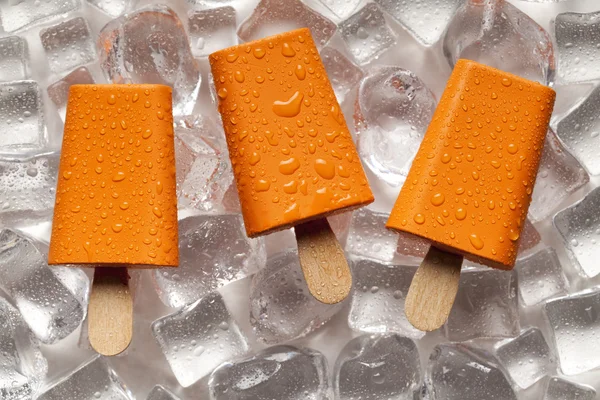 Orange ice lollies on ice cubes