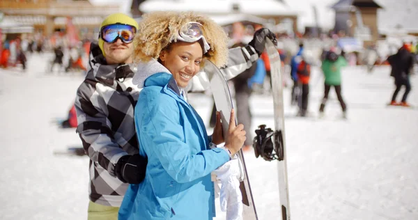 Man flirting with woman holding snowboard