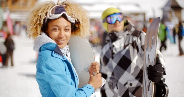 Man flirting with woman holding snowboard