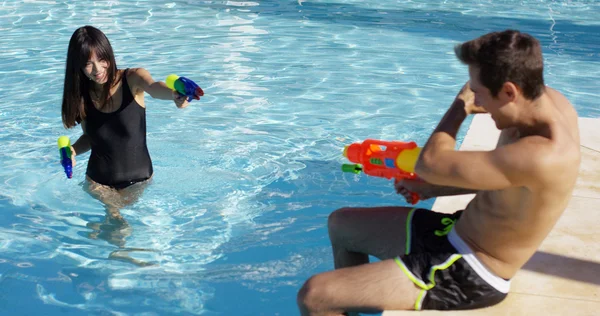 Adults shooting water guns at each other