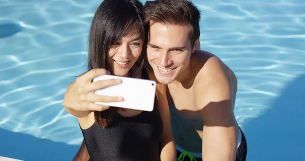 Couple take photo while standing in pool