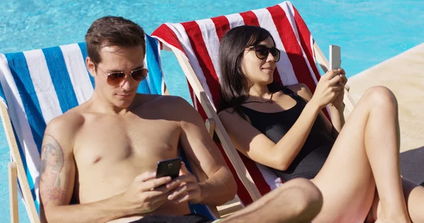 Couple using phones at swimming pool