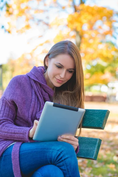 Young woman using her tablet in an autumn park