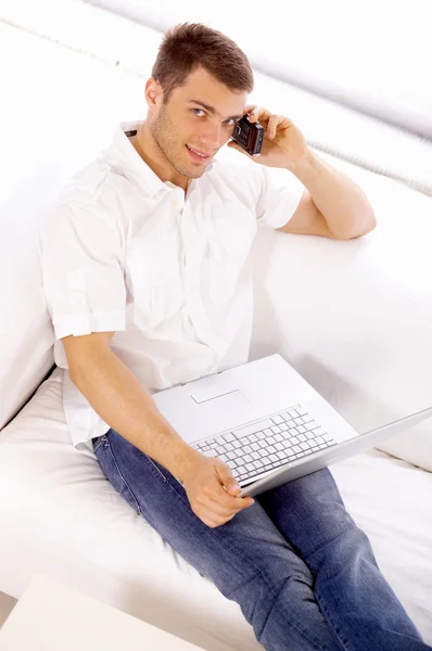 Young Salesman on Couch Using Phone and Laptop