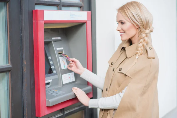 Pretty blond woman drawing money at an ATM