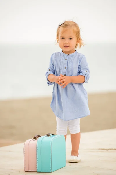 Adorable little girl with two small suitcases