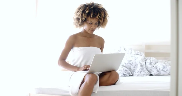 Woman with laptop computer sitting on bed