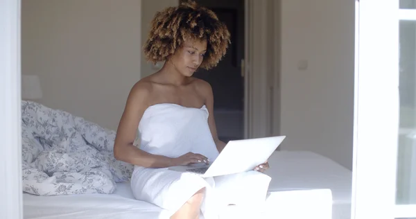 Woman with laptop computer sitting on bed