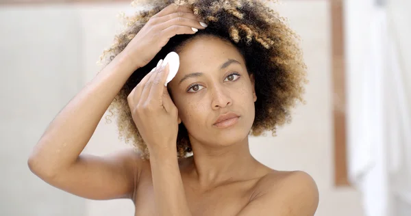 Woman cleaning face with cotton pad