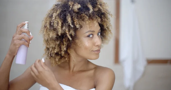 Woman in towel using hair spray