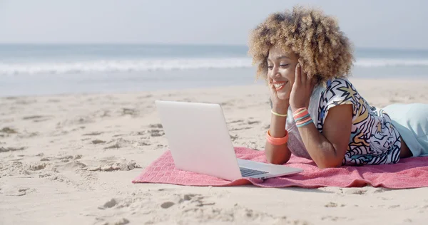 Girl lying on beach with laptop