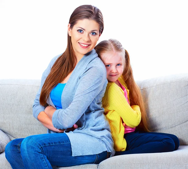 Mother with daughter seat on sofa back to back.