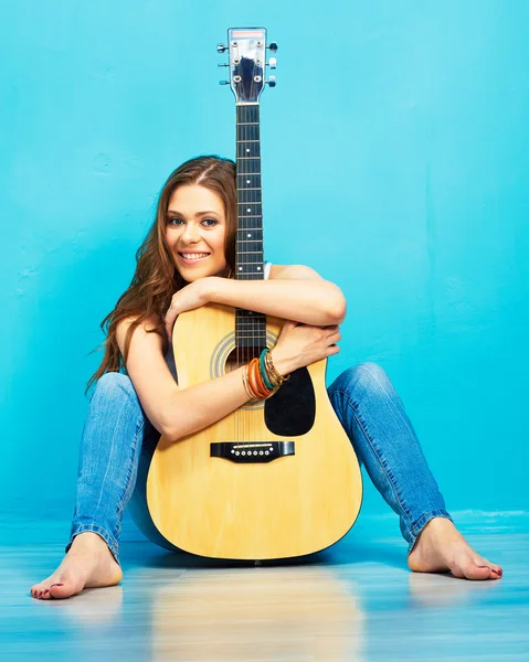 Girl with acoustic guitar sitting on a floor