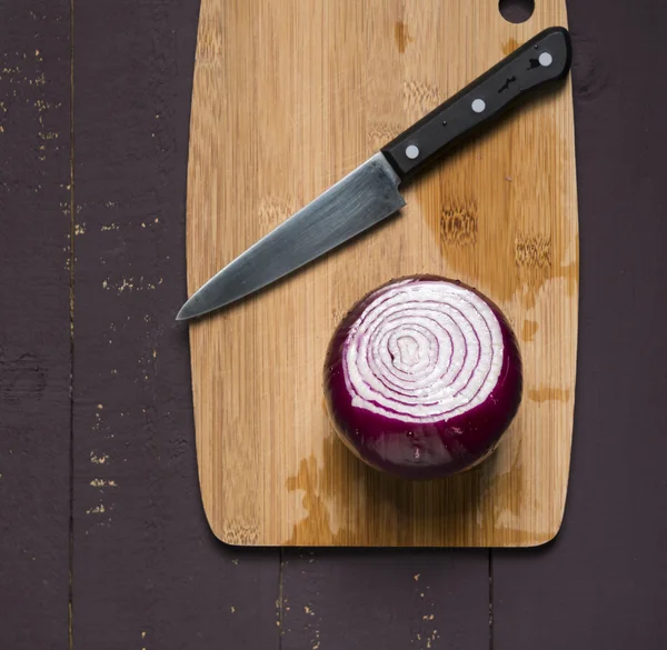 Fresh cut red onion for cooking on wooden board.