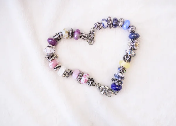 String of beautiful glass beads in heart shape on white cloth