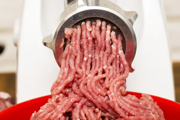 Closeup of minced meat coming out from grinder.