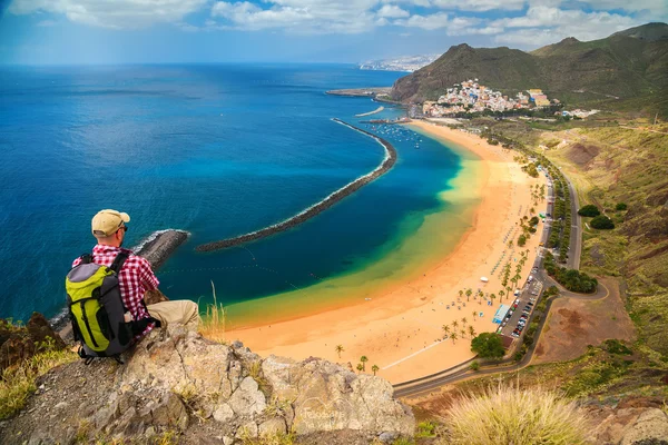 Tourist man sitting on the edge of a cliff
