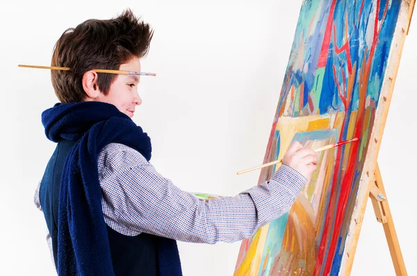 Artist school boy painting brush watercolors portrait on a easel