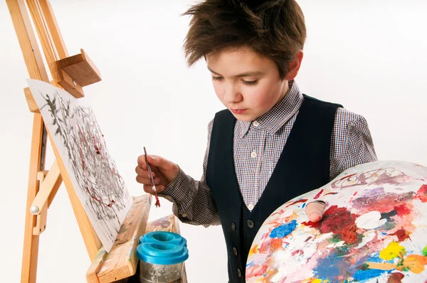 Artist school boy painting brush watercolors portrait on a easel