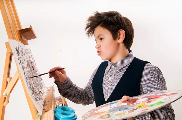 Artist school boy painting brush watercolors portrait on a easel