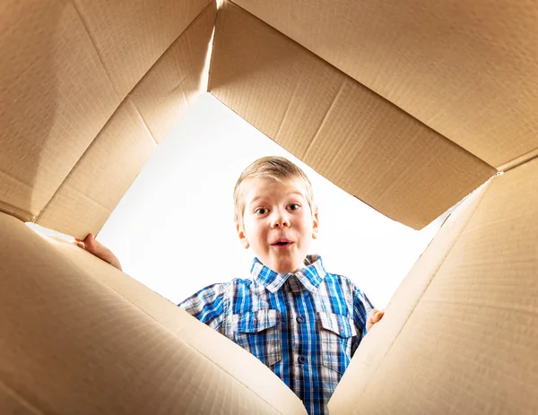 Child opening cardboard box and looking inside with surprise