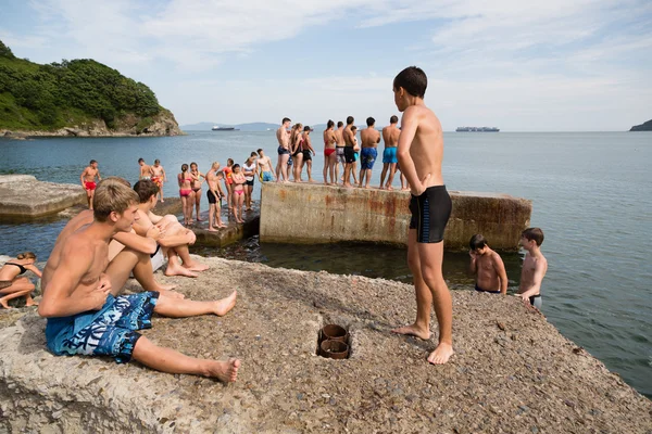 Joyful boy and girl jumping into the sea from old pier