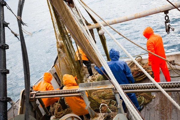 Fishermen in waterproof clothing on the deck of the fishing vess