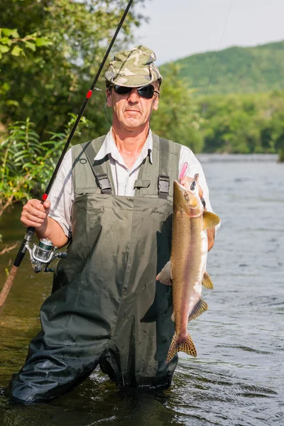 Happy fisherman keeps caught salmon