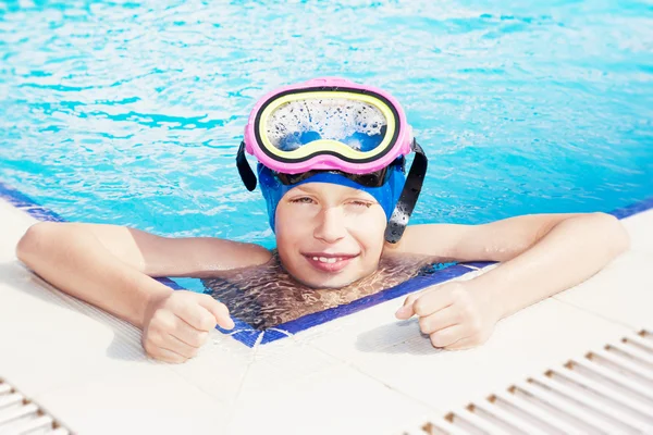 Beautiful happy child wearing a swimming mask in a swimming pool smiling
