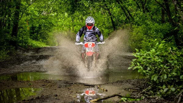 Enduro moto in the mud with a big splash