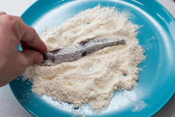 Cooking beef liver covered in flour on a frying pan.