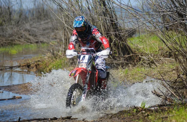 Enduro motorcycle rides through the mud with a big splash