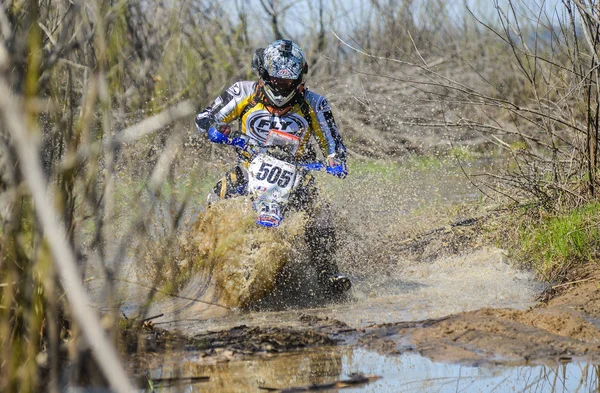 Enduro motorcycle rides through the mud with a big splash