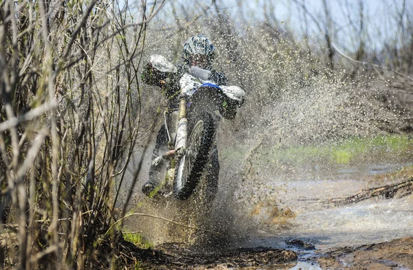 Enduro motorcycle rides through the mud with a big splash