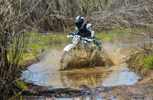 Enduro motorcycle rides through the mud with a big splash